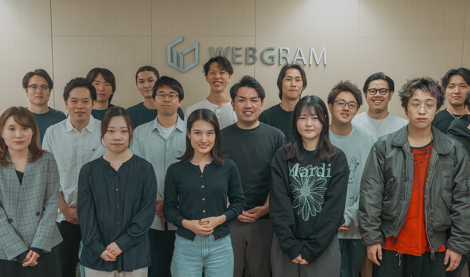 WEBGRAMのロゴを背にエントランスに集合したメンバーたち
